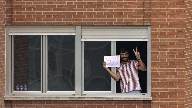 Uno de los aislados en el hospital Carlos III de Madrid muestra que no tiene fieber con un cartel en el que figura su temperatua: 36,1º