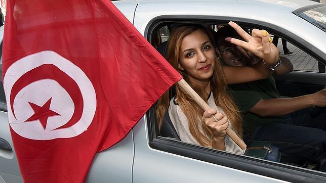 Una mujer ondea una bandera tunecina durante la jornada electoral de ayer