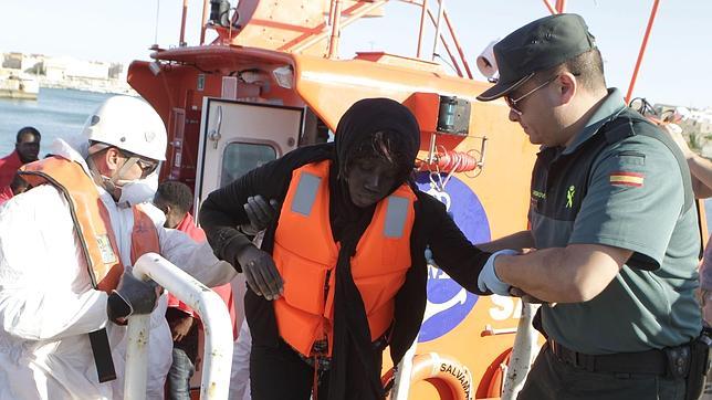 Un agente de la Guardia Civil y de Cruz Roja ayudan a una inmigrante