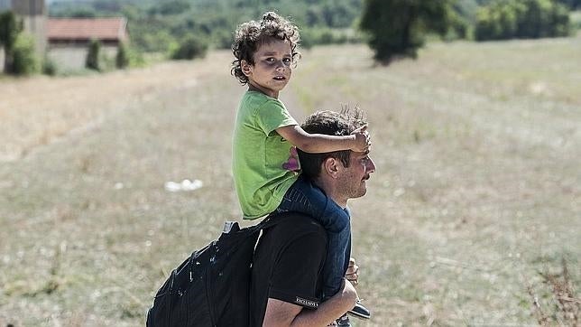 Un inmigrante camina con un niño a hombros cerca de la ciudad de Miratovac, en Serbia