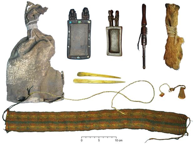 Paquete ritual con bolsa de cuero, tabletas de tabaco de madera tallada y tubo de tabaco con trenzas de cabello humano, bolsa de tres hocicos de zorro, espátulas de hueso de camélido, diadema textil de colores y cuerdas de lana y fibra