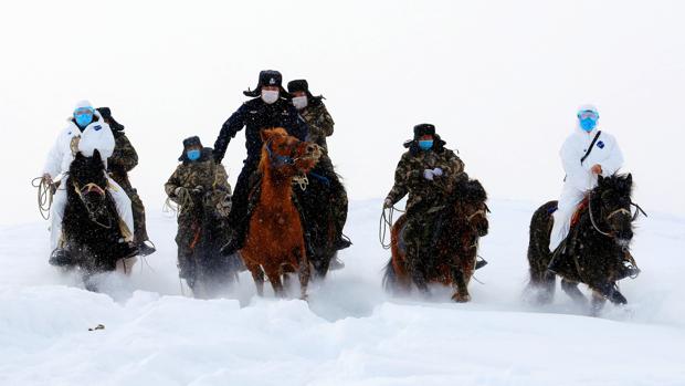 Autoridades fronterizas cabalgan a través de la nieve para informar a los residentes sobre la epidemia de coronavirus en una región montañosa de Altay, en Xinjiang, China, el pasado 19 de febrero