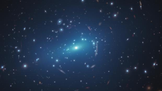 La imagen del Hubble muestra el cúmulo de galaxias MACS J1206. Incrustadas en el cúmulo hay imágenes distorsionadas de galaxias de fondo distantes. Esas distorsiones son causadas por la materia oscura del cúmulo, cuya gravedad dobla y magnifica la luz de las galaxias lejanas, un efecto llamado lente gravitacional