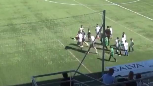 El niño lesionado es retirado del campo por el delegado de su equipo