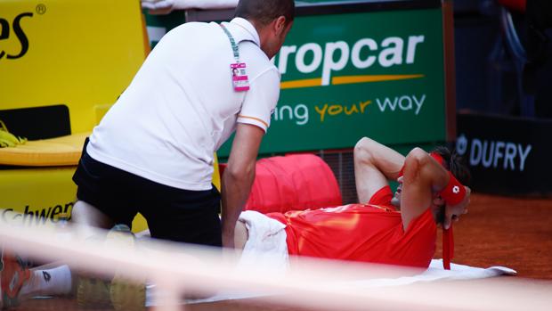 Un fisioterapeuta atiende a David Ferrer en la pista