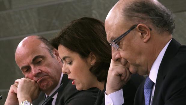 La vicepresidenta del Gobierno, Soraya Sáenz de Santamaría, acompañada por los ministros de Economía y Competitividad y de Hacienda, Luis de Guindos (i) y Cristóbal Montoro