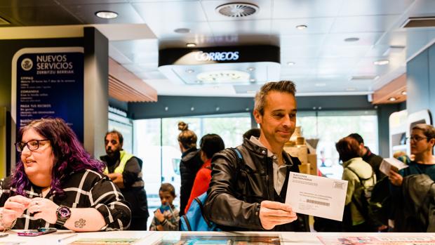 Personas gestionando el voto por correo en una oficina de Correos