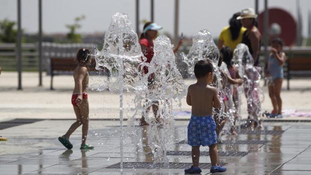 Un grupo de niños se refresca en una fuente