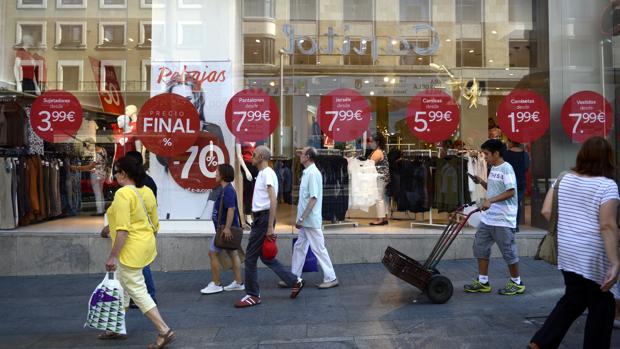 Varios compradores pasan por delante de un escaparate son rebajas, en la Gran Vía