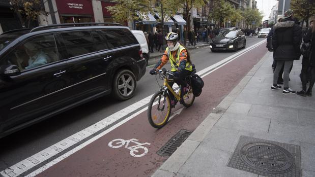 Una bicicleta circula junto a un coche en la calle de Mayor
