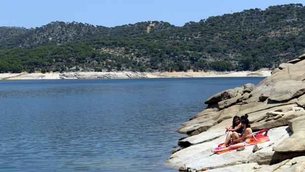 Dos bañistas toman el sol en una orilla del pantano de San Juan