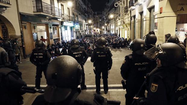Un grupo de antidisturbios de la Policía frente a una multitud de jóvenes partidarios de la okupación