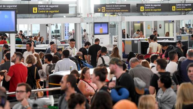 Decenas de pasajeros, esperando para pasar los controles, este viernes en El Prat