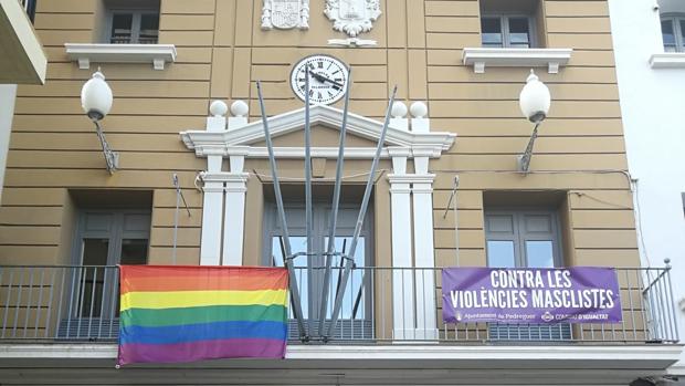 Imagen difundida por la CUP de Pedreguer en sus redes sociales de la fachada del Ayuntamiento con la bandera LGTBI y una pancarta contra la violencia machista