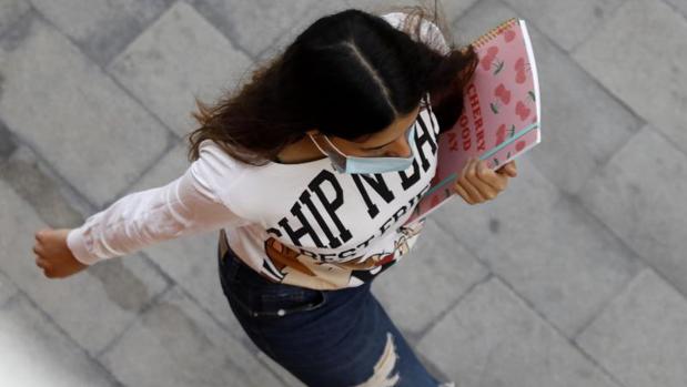 Una adolescente camina con mascarilla por una calle de Alicante