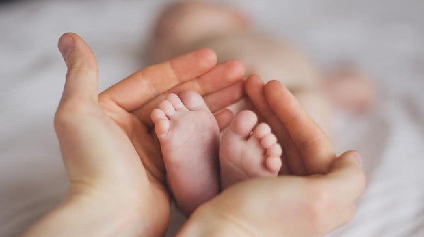 Talones de bebé, sostenidos por las manos de una mujer
