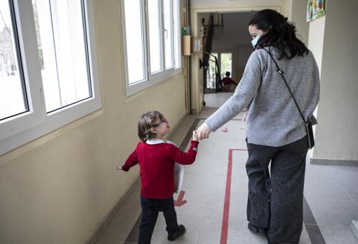 La orientadora de infantil lleva de la mano a una niña con Síndrome de Down