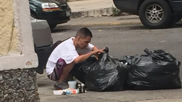 Un hombre hurga en la basura en busca de comida en Caracas