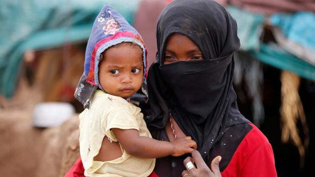 Una niña transporta a un niño en un campamento para desplazados en Yemen