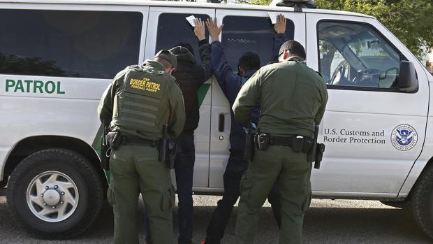 Una patrulla cachea a dos detenidos en la frontera, en 2017