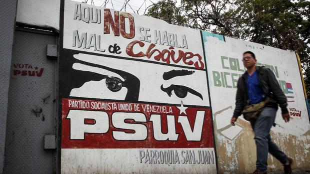 Un hombre pasa frente a un mural chavista en un barrio de Caracas