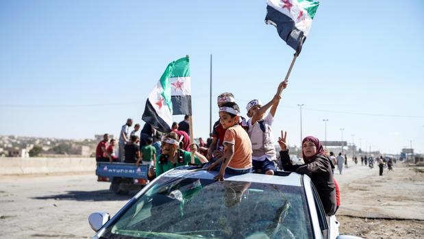 Varias personas ondean banderas sirias revolucionarias durante una protesta en la localidad de Kafr Nabl, en la provincia de Idlib