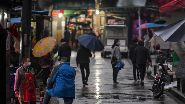 Las personas usan mascarillas y guardan la distancia social como medidas preventivas contra la propagación del Covid-19, en una calle de Wuhan