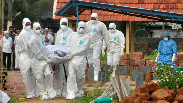 Médicos y familiares con trajes de protección cargan con el cuerpo de una víctima del virus Nipah en Kozhikode, en el sur del estado de Kerala, en la India