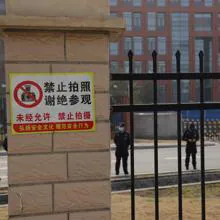 Tras las vallas con letreros prohibiendo tomar fotos, la seguridad china hace guardia ante el Instituto de Virología de Wuhan durante la visita de los expertos de la OMS el año pasado