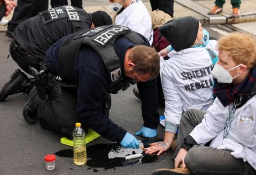 Un policía quita este miércoles el pegamento de la mano de un activista de Rebelión Científica que bloquea un puente en el centro de Berlín, Alemania