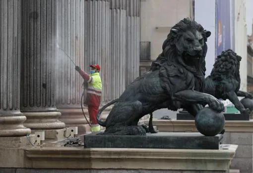 Un operario limpia las manchas de pintura roja de la fachada del Congreso de los Diputados